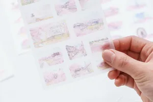 Close-up of translucent watercolor sticker sheet with cute landscape illustrations for journals.