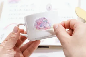Close-up detail shot of decorative watercolor house sticker applied on a white ceramic mug.
