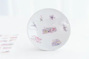 Close-up of decorative watercolor cherry blossom stickers on a white ceramic bowl for crafts.