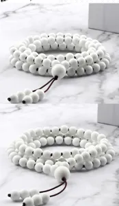 Gros plan détaillé de l'élégant bracelet de prière en 108 perles blanches texturées.