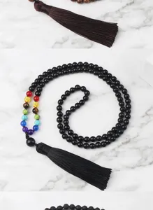 Gros plan détaillé du collier de perles chakra bohème noir avec un pompon élégant.