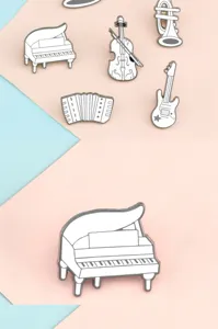 Close-up detail of white musical instrument enamel pins featuring piano and violin designs.