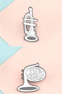Close-up detail of mini musical instrument enamel pins set in elegant white design.