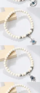 Bracelet de perles mauvais œil avec breloques main de fatma et tortue sur perles blanches craquelées.