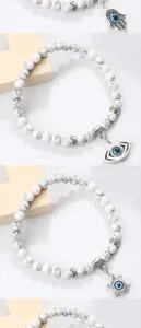 Bracelet de perles marbrées blanches avec œil turc, main de Hamsa et pendentif tortue argent.