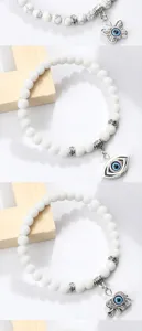 Gros plan sur les détails du bracelet mauvais œil avec perles blanches et pendentifs argentés.