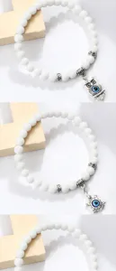 Bracelet de perles blanches elegant avec breloque hibou et tortue oeil malefique.