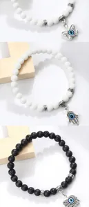 Vue de détail bracelet mauvais œil main de Fatima, perles résine blanche et lave noire.