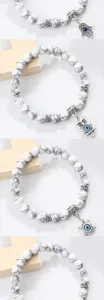 Détails en gros plan du bracelet en perles de pierre craquelée blanche et breloques œil.