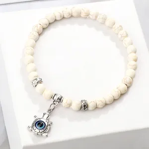 Bracelet de perles blanches avec un joli pendentif tortue mauvais œil, élégant et chic.