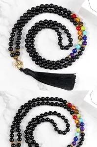 Detailed view of black obsidian bead necklace featuring colorful chakra stones and tree of life.