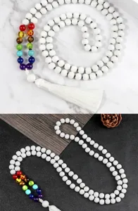 Dettagli in primo piano della lunga collana di perline bianche con perline chakra colorate e nappa.