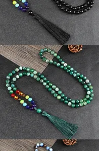 Primo piano di collana di perle con nappa multistrato, pietre chakra e dettagli in ossidiana.