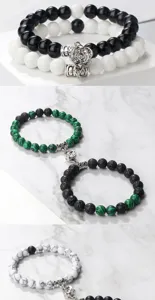 Gros plan montrant des bracelets de couple en perles magnétiques avec breloques fleurs et pierres.