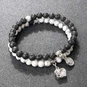 Pulsera de cuentas de doble capa con piedra volcánica negra, turquesa y dije de rosa.