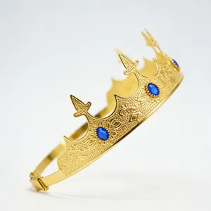 Detail shot of men's royal gold crown, featuring embossed patterns and embedded blue gems.