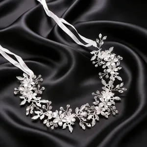 Primer plano detallado de la diadema de novia plateada con diseño floral y cintas blancas.