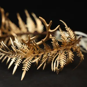 Détail du serre-tête doré avec bois de cerf et feuilles dans un style féerique et élégant.