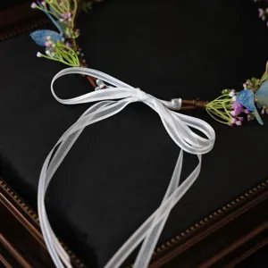 Detail view of floral hair wreath with blue butterflies and white ribbon for wedding or cosplay.