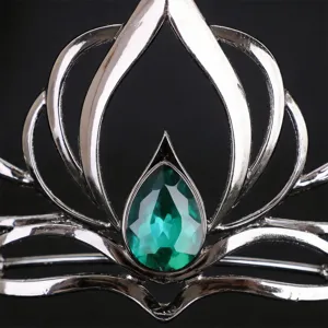 Primo piano dettagliato di una tiara retrò in metallo argentato con gemma verde a goccia al centro.