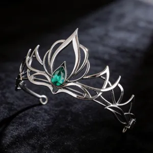 Primo piano dettagliato di una tiara corona gotica retro scura con cristallo verde a goccia.