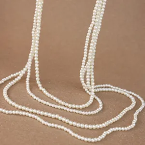 Dettaglio della catena di perle bianche multistrato che mostra un drappeggio elegante.