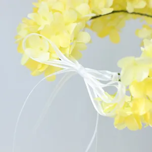 Yellow artificial hydrangea floral headband close-up, sweet wedding hair accessory with white ribbon.