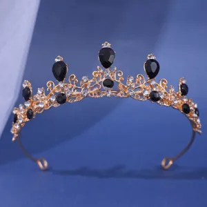 Gros plan détaillé du diadème doré avec des strass noirs en forme de goutte et cristaux.