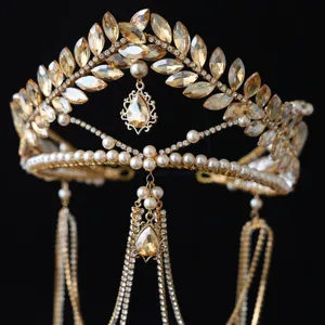 Detalle de tiara de estrás hoja de oro, elegante corona de novia con flecos de perlas.