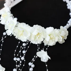 Close-up view of white floral hair garland featuring delicate pearl tassels for bridal wedding wear.