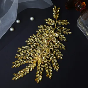 Detailed close-up of gold rhinestone bridal hair piece, handcrafted leaf design accessory.