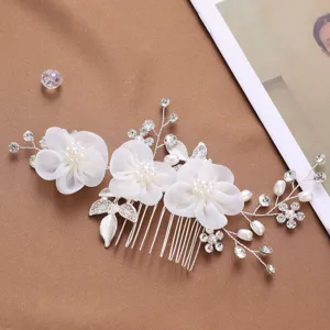 Détail de peigne à cheveux de mariée élégant avec fleurs en mousseline blanche, perles et strass.
