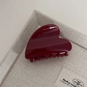 Detailed view of a glossy dark red heart-shaped hair claw clip, elegant minimalist daily accessory.