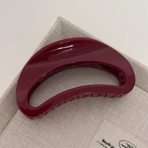 Burgundy crescent hair claw clip close-up shot, elegant resin shark clip for styling.