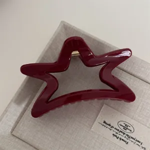 Red star hair claw clip detail shot showing glossy finish and metal spring mechanism