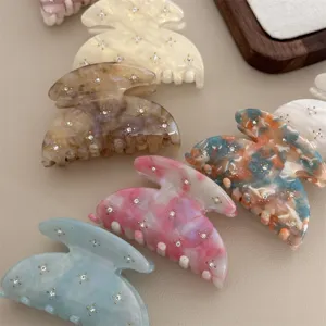 Close-up detail of colorful acetate hair claws with sparkling rhinestones for cute styling.