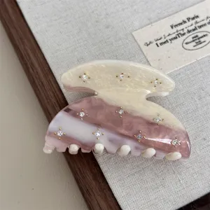 Detail of sweet acetate hair claw clip with sparkly rhinestones and retro semi-circle design.