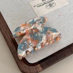Detailed view of colorful marbled acetate hair claw clip with rhinestones, stylish hairpin.