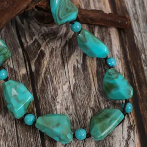 Closeup of vintage turquoise irregular beaded detail on rustic wooden background surface.