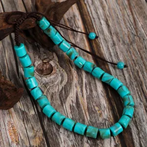 Detailed close-up of a retro turquoise beaded necklace with adjustable brown cord on wood.