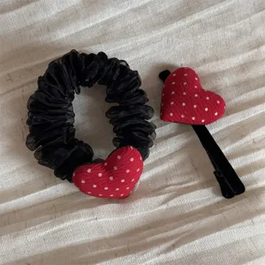 Detailed shot of red polka dot heart hair clip and black mesh scrunchie set, sweet fabric design.