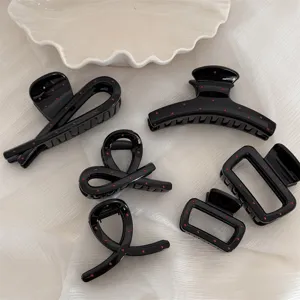 Vue détaillée de pinces à cheveux noires à pois, designs géométriques mignons pour femmes.