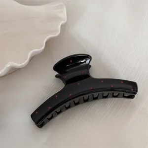 Pince à cheveux noire à pois rouges, gros plan détaillé d'accessoire de cheveux mignon.