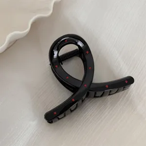 Gros plan détaillé d'une pince à cheveux noire élégante avec des pois rouges mignons.