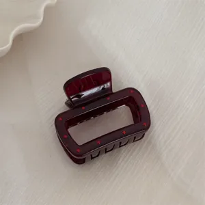 Vue détaillée d'une jolie pince à cheveux rectangulaire rouge foncé avec des pois pour femmes.