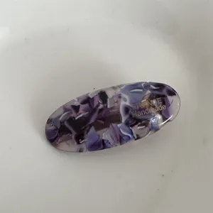 Elegante fermaglio per capelli ovale in acetato viola con dettagli dorati artigianali.