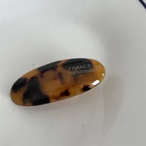 Primo piano dettagliato della superficie dell'elegante fermaglio in acetato tartaruga e testo.