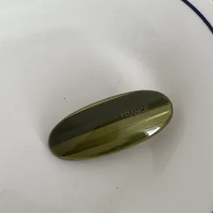 Vista dettagliata dell'elegante fermaglio per capelli ovale in acetato verde scuro.