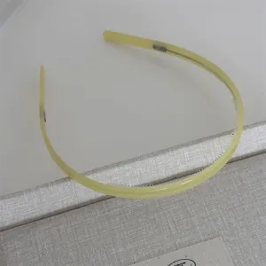 Minimalist pale yellow acetate headband with teeth, smooth finish, elegant daily hair accessory.