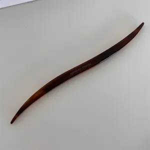 Detail view of a stylish tortoiseshell acetate hair stick, elegant curved hairpin for chic buns.